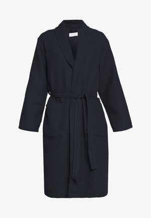 Mörkblå waffle-texturerad morgonrock med långa ärmar, en sjalkrage och ett matchande bälte. Har två framfickor för funktionalitet.