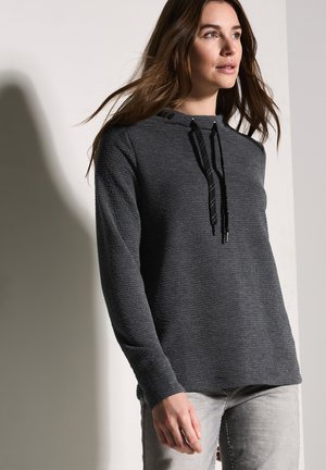 Felpa con cappuccio grigio scuro, dalla vestibilità ampia, con cappuccio regolabile e maniche lunghe, abbinata a jeans grigio chiaro.