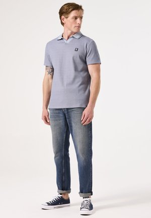 Grijs polo shirt met een contrasterende kraag, korte mouwen en een klein logo. Gecombineerd met lichtblauwe spijkerbroek en marineblauwe sneakers.
