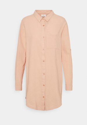 Koszula z długim rękawem w jasnym brzoskwiniowym kolorze, zapinana na guziki, z kołnierzykiem i pojedynczą kieszenią na piersi, przedstawiona na jednolitym białym tle.