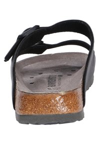 Black open-toe sandal with an adjustable strap, cork footbed, textured gray insole, and a sturdy black rubber sole.