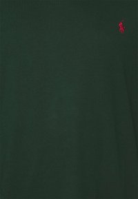 Dark green cotton t-shirt with a short sleeve design. Features a small red embroidered logo on the left chest area. Smooth texture.