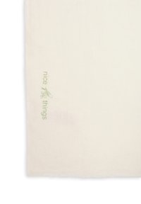 Nappe en coton naturel de couleur blanc cassé, ornée d'un texte brodé en vert "nice things", avec une texture douce et un bord frangé.