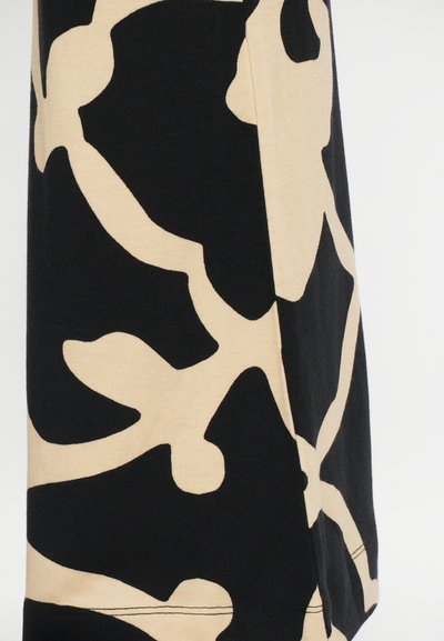 Zwarte textiel met grote beige abstracte patroonen, met een gladde textuur en zichtbare stiksels aan de zoom, die een losvallende vorm vormt.