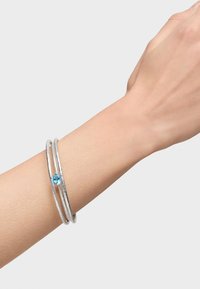 Bracciale rigido in argento con tre fasce texture, decorato con un piccolo cristallo azzurro tondo su una delle fasce.