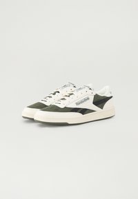 Green and white sneakers with a suede and leather upper, featuring black accents, textured sole, and a branded tongue.