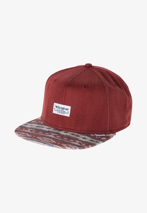 Rode snapback pet met gestructureerde stof en een effen klep met aardetinten en een wit rechthoekig logoplaatje op het voorpaneel.