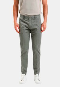 Pantaloni di cotone grigi con vestibilità slim, dotati di chiusura a bottone e tasche frontali, abbinati a scarpe da ginnastica bianche.