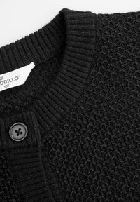 Czarny sweter kardigan z dzianiny z fakturowanym wzorem, prążkowanym kołnierzem i czarnym zapięciem na guziki. Widoczna metka z nazwą marki i rozmiarem.