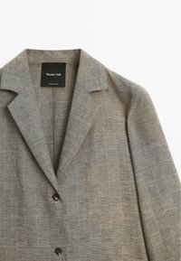Blazer marron clair avec motif à carreaux subtil, revers crantés, deux boutons et étiquette Massimo Dutti à l’intérieur du col.