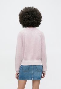 Rozā ribota trikotāžas džemperis ar raglāna piedurknēm, kombinēts ar zilu džinsa svārku. Redzamas šuvju detaļas un vaļīga piegriezuma vidukļa daļā.