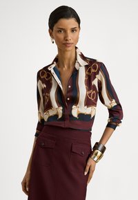 Πουκάμισο με μακριά μανίκια και κουμπιά, με πολύχρωμο σχέδιο αλυσίδας. Κατασκευασμένο από λείο ύφασμα, διαθέτει μυτερό γιακά και μανσέτες σε αντίθετο χρώμα.