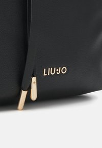 Zwarte gestructureerde leren tas met gouden ritsen en het gouden LIU·JO merklogo op de voorkant in de onderste hoek.