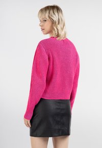 Fuchsia-gerippter Strickpullover mit langen Ärmeln, kurzem Design und rundem Halsausschnitt, kombiniert mit einem schwarzen Leder-Minirock.