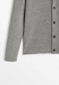 Cardigan gris à manches longues avec boutons noirs, tissu tricoté doux, présenté de la manche jusqu'au milieu du torse sur un fond blanc.