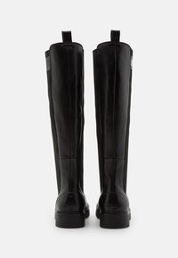 Czarne skórzane kozaki sięgające kolan o gładkiej fakturze, z lekko połyskującą powierzchnią, solidnymi podeszwami i pętlami do ściągania u góry. Boczne elastyczne panele dla lepszego dopasowania.