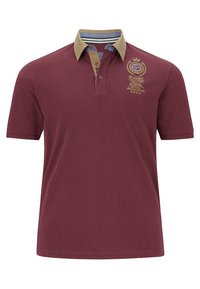Maroon polo shirt with a contrasting tan collar, featuring a ribbed texture, three-button placket, and embroidered logo design on chest.