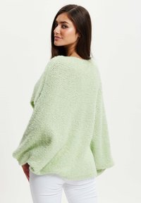 Green textured oversized sweater with batwing sleeves, made from soft yarn, featuring a loose, relaxed fit and ribbed detailing.