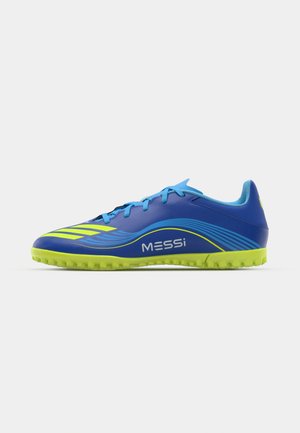 Modre nogometne čevlje s elegantnim dizajnom, ki vključuje neon zelene poudarke, izrazit branding "MESSi" in teksturiran podplat za oprijem.
