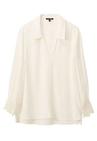 Blouse blanche avec un col, décolleté en V et manches trois-quarts. Présente des accents brodés décoratifs sur les poignets. Tissu doux.