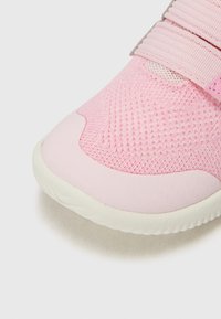 Ljusrosa sneaker med strukturerad meshtopp, gummisula och kardborreband. Har en slät tåkappa och subtila accenter.