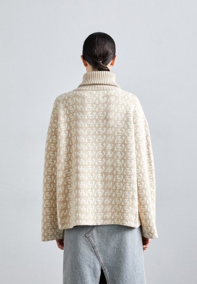 Beige mönstrad stickad tröja med hög ribbad krage, oversized siluett och mjuk textur, ihop med en gråjeanskjol med sprund.