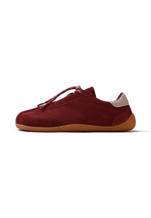 Zapato casual de ante rojo con suela de goma marrón clara, parche beige en el talón y cierre con cordones elásticos con ajuste, mostrado de lado sobre fondo blanco.