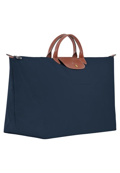 Navy blue tote bag made of nylon with brown leather handles and flap. Features a zip closure and a rectangular shape.