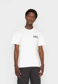 White cotton T-shirt with short sleeves. Features "SCARFACE" printed in black on the left chest area. Simple crew neck design.