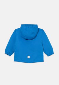 Blaue Windbreaker-Jacke mit Kapuze, elastischen Bündchen und einem quadratischen Logo-Patch auf der Rückseite. Glatte Textur und leichtes Design.