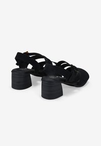 Sandalias de ante negro con tacón cuadrado, tiras entrelazadas y detalle de hebilla. Las suelas texturizadas y la punta redondeada aumentan la comodidad y el estilo.