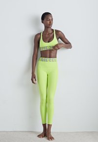Neongrön sport-bh och leggings med en logoband. Tyget ser glatt och stretchigt ut, designat för träning.