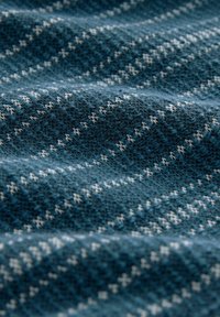 Textile fabric in dark teal with a textured surface, featuring a geometric white pattern. Soft texture with slight stretch and dimension.