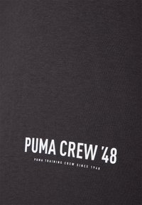 Tamsiai pilka medvilninė marškinėliai su balta užrašu "PUMA CREW '48". Numatytas minkštas paviršius ir švarus dizainas, tinkantis kasdieniam dėvėjimui.