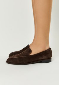 Mocasini din suede maro, cu toc mic și vârf ascuțit, având o textură netedă și fără hardware sau embellishementuri vizibile.