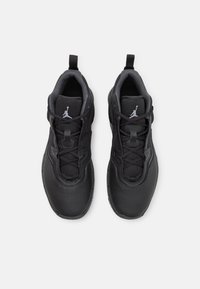 Ett par svarta sportskor med snören, ventilerande mesh-tungor och vita Jumpman-logotyper på en vit bakgrund.