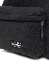 Zwarte fleece rugzak met ritssluiting aan de voorkant en een Eastpak-logo patch. Zachte textuur met een stevig ontwerp.