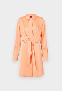 Robe col classique en tissu doux pêche, avec une fermeture à boutons sur le devant, des manches longues et un détail de taille nouée pour une silhouette froncée.