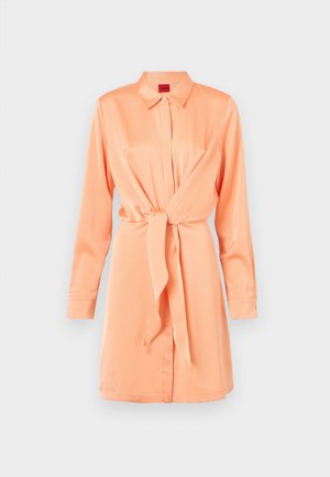 Φόρεμα με γιακά από απαλό ύφασμα ροδακινί, με κλεισιμο μπροστά με κουμπιά, μακριά μανίκια και λεπτομέρεια με δέσιμο στη μέση για σφιχτή σιλουέτα.