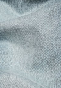 Světle modrá denimová látka s hladkým povrchem, s jemným vzorem rybí kosti a mírně bledými oblastmi. Vhodná pro oděvy.