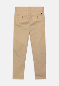Chinos color khaki realizzati in un morbido tessuto di cotone, design slim fit, cinque tasche con chiusure a bottone e un logo discreto sull'orlo posteriore.