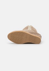 Botas de ante color suela con una suela de goma texturizada, que presenta un acento tejido a lo largo del borde y un patrón de olas en la suela exterior.