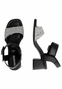 Sandali neri con tacco, dotati di una fascetta a zigzag bianco e nero. Presentano un tacco a blocco e una cinghia alla caviglia con chiusura a fibbia. Texture liscia.