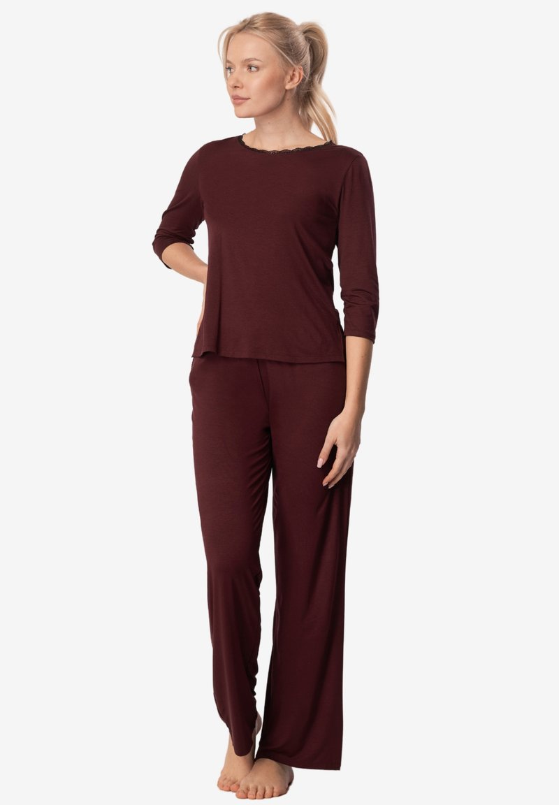 Bordowy zestaw piżamowy składający się z bluzki z długim rękawem o falbaniastym dekolcie oraz luźnych spodni, wykonany z miękkiego, gładkiego materiału.