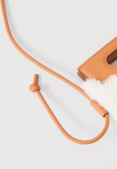 Tan læder clutch med en tekstureret hvid pelsdetalje, der har en tynd rem og en rektangulær åbning, der viser kontrasterende materialer.