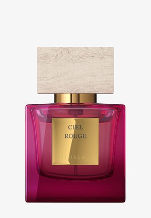 Kwadratowa różowa szklana butelka perfum z dużą jasną drewnianą zakrętką i złotą etykietą z napisem "Ciel Rouge Rituals".