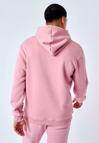 Sudadera con capucha rosa, hecha de un tejido suave, que presenta un corte relajado, puños acanalados y una gran capucha con un escote redondeado.