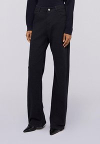 Černé široké kalhoty vyrobené z denimu, s předním zapínáním na knoflík, poutky na opasek a bočními kapsami. Hladká struktura s jemným prošíváním.