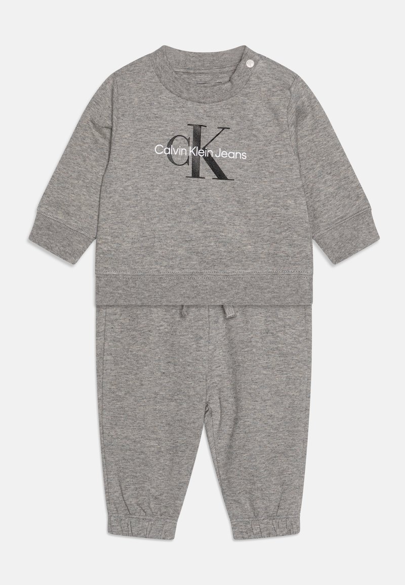 Tuta in cotone grigio con girocollo, maniche lunghe e polsini elastici. La maglietta presenta un logo nero "Calvin Klein Jeans".