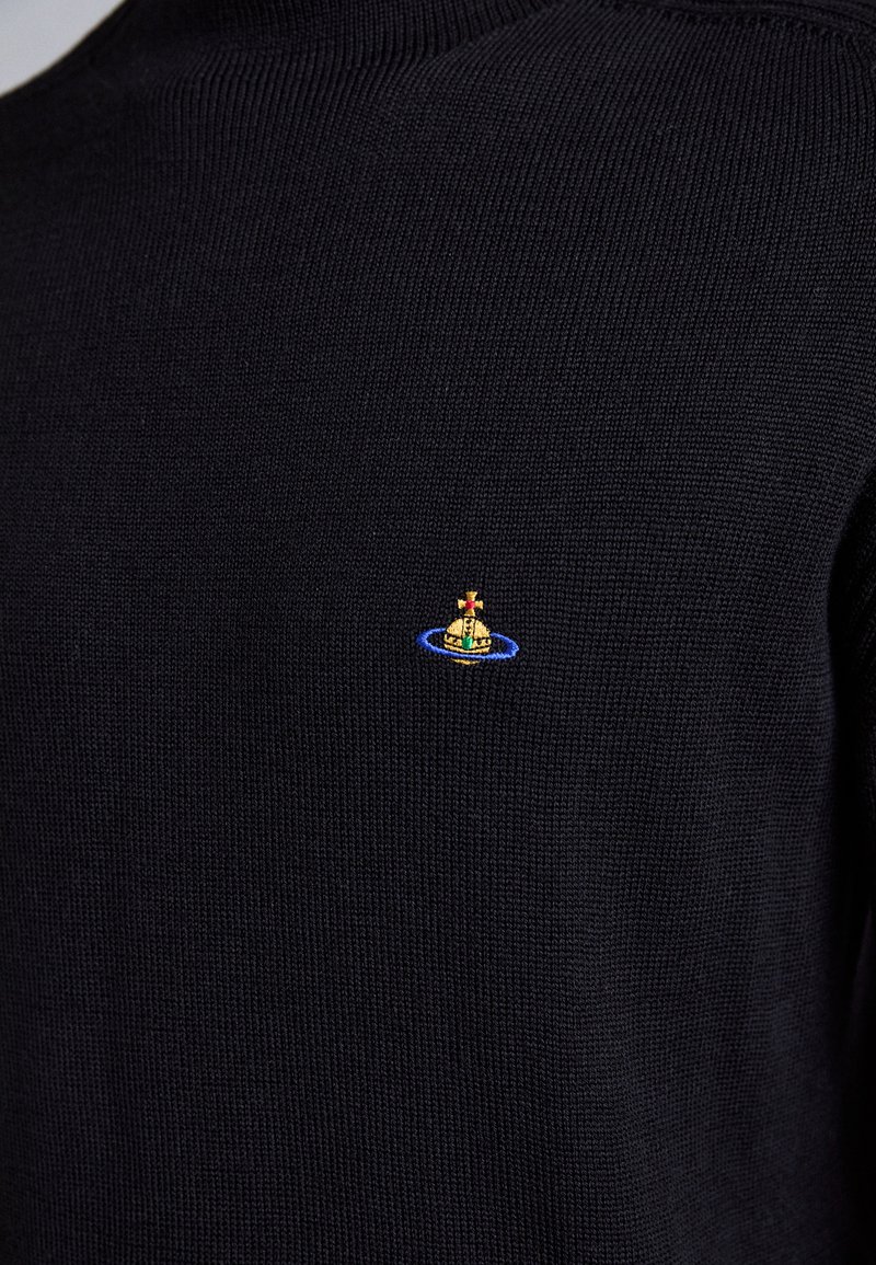 Schwarzer Strickpullover mit kleinem gesticktem Logo, das eine goldene Kugel zeigt, die von einem Kreuz gekrönt wird, umgeben von einem blauen Ring auf der Brust.